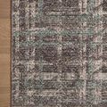 Close-up of rug corner showing fringed edge and textured plaid pattern on wooden floor