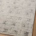 Diagonal angled view of rug on hardwood floor emphasizing soft grey tones and pattern