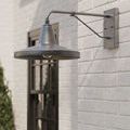 Mariner sconce mounted outdoors on white brick next to window with greenery in foreground