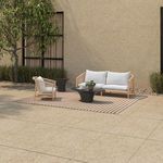 Outdoor scene with Kuna Sofa and matching armchair on patio, featuring beige tiled floor and greenery