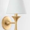 Close-up of upper sconce section showing white fabric shade and gold fluted texture below