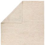 Top corner of rug folded over to reveal reverse side with contrasting woven texture