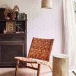 Relic pendant light styled in a cozy room with white brick wall, woven leather chair, wooden stump side table, and sheer c...