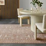 Taupe rug under a cream round dining table with wood and boucle dining chairs in modern room