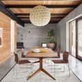 Beverly rug shown in a contemporary dining room with wooden table, wire-frame chairs, and concrete and wood walls
