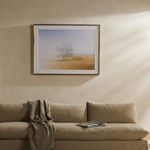 Framed photograph displayed above modern beige sectional sofa in warm ambient lighting