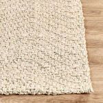 Corner of rug on hardwood floor highlighting thick handwoven jute fibers and edge detail