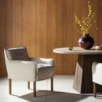 Addington armchair shown in wood-paneled dining room beside round pedestal table with vase