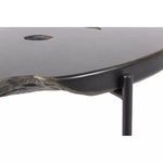 Side detail of teak root with raw wood grain visible where iron frame meets table top