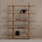 Styled front view of Casey bookcase with decorative objects on shelves against paneled wall background