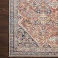 Close overhead view of rug corner on dark wood floor focusing on intricate border and floral details