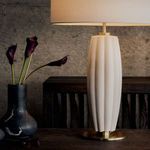 Close-up side view of white Crocus Ceramic Table Lamp illuminated next to black marble vase with dark flowers