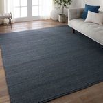 Lifestyle image of Ryker rug beneath couch near bright window and decorative plants