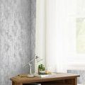 soft silver wallpaper applied on wall beside window with white curtains and wooden desk with lamp and plants