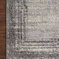 Close-up corner view of rug on dark wood floor emphasizing muted charcoal and pebble colors and woven details