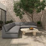 Dark gray Miles outdoor sectional with chaise, shown from left angle on textured stone tile patio.