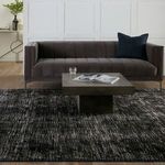 Modern living room setting with charcoal sofa, dark blue pillow, concrete square coffee table on rug