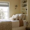Close bedroom view with Harvey Ivory Pillow visible among various textured pillows on a bed