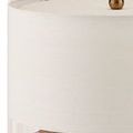 Close-up of beige fabric drum shade with visible fine weave and brass finial top