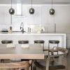 Three Odyssey Pendants hanging over white kitchen island with wooden dining table and chairs in foreground