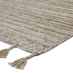 Close-up corner view showing textured flatweave surface and braided light taupe fringe
