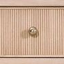 Macro detail of fluted wood texture and metal knob on drawer front