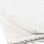 Close-up of folded throw blanket highlighting soft plush back texture and waffle weave front edge