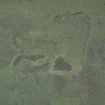 Macro detail of varied dark patches and textured areas on muted green abstract painting surface