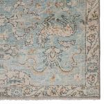 Close-up of rug corner highlighting detailed wildlife and fleurette design in muted teal and gold