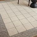Close-up angled view of Francis rug with chair and table legs showing wool texture and stitched pattern