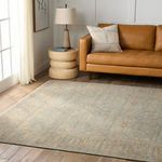 Rug styled in living room with leather sofa, beige sculptural side table, and floor lamp