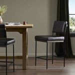 Benton Stool positioned beside wooden table in modern room with natural light and dark curtains