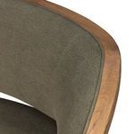Close-up of top edge of chair back cushion wrapped in olive linen-blend fabric with oak frame