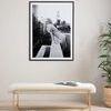 Photo hung above a bench in a light room with wooden floor and potted plant