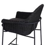 Close-up of chair’s tightly woven wicker armrest and dark fabric cushion edge