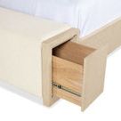 Close-up of open storage drawer built into bed's footboard with wooden interior and metal slides