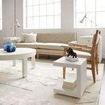 Styled in bright living room with beige sofa, wood armchair, and decorative objects on table