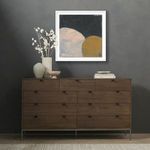 Painting positioned high on wall above dark wooden dresser with dried white flowers and stone bowls on left side
