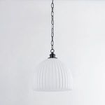Fluted pendant light hanging against plain white wall showing full fixture and chain from side angle
