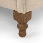 Detailed view of wooden turned sofa leg with cream fabric above
