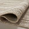 Rug partially curled to reveal thickness and woven texture of rectangular pattern