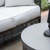 Side view focus on loveseat seat cushion and round gray patio table surface
