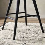 Close-up of the side and rear tapered legs meeting the floor on a textured white rug