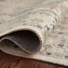 Partially rolled edge of the rug reveals the tightly woven backing and stitched edging on dark floor