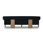 Back view of sofa displaying two wide wooden support legs and velvet back panel