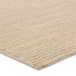 Angled close-up of rug corner emphasizing woven natural fibers and stitched edge
