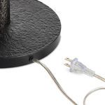 Close-up of textured black metal base with power cord and clear plug detail