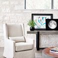 Mercury Console styled in a bright room next to beige armchair, decorative plant and framed art on table