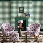 Wallpaper applied on walls around a green fireplace in a living room setting with patterned armchairs and geometric tiled ...