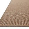 Low-angle close-up showing the textured woven rust and beige pattern and border detail